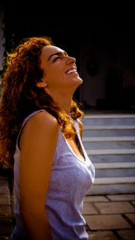 Side view of a happy woman smiling brightly outdoors, exuding joy and confidence.
