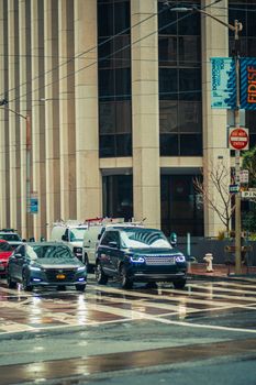 City street view showcasing vehicles on a wet day with skyscrapers in the background.