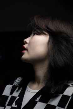 Artistic side profile of Asian woman wearing a checkered sweater, capturing elegance.