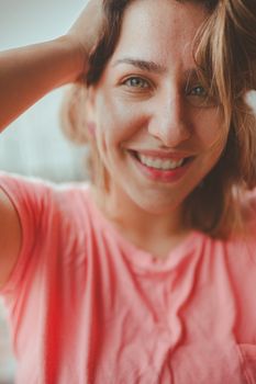 Close-up portrait of a smiling woman in a casual pink shirt, looking happy and natural.