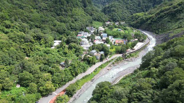 Stunning aerial view of a lush river valley and village in Hsinchu County, Taiwan.