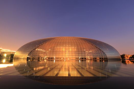 The iconic dome-shaped National Centre for the Performing Arts in Beijing, China, illuminated at twilight.
