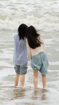 Two young women enjoying the waves at the beach, capturing a moment of friendship by the sea.
