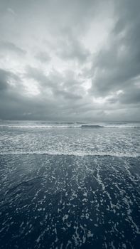 A moody winter beach scene with a cloudy sky over the ocean.