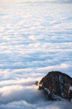 A breathtaking aerial view of a peak rising through a sea of clouds, showcasing Leshan's dramatic landscape.