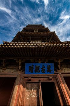 Explore the architectural beauty of an ancient wooden pagoda in Shaanxi under a vivid sky.