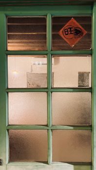 A green vintage door featuring frosted glass panels and a Chinese good fortune symbol.