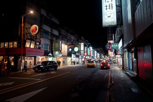 Bustling night street in Taipei with bright city lights and urban activity.