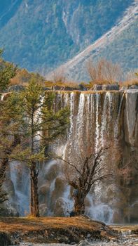 Stunning view of a waterfall in Lijiang, surrounded by lush greenery and rocky formations.