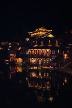 A traditional Chinese building beautifully lit up at night reflecting on water in Beijing.