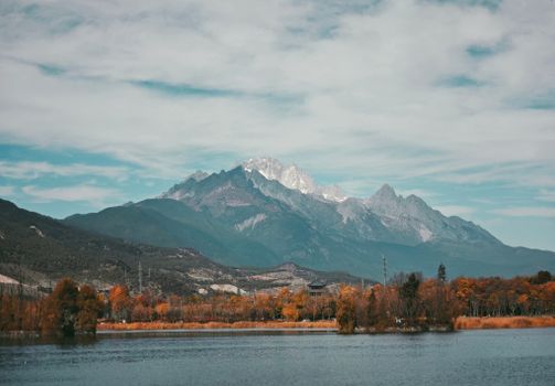 A breathtaking view of Jade Dragon Snow Mountain in autumn, capturing vibrant fall colors and serene waters in Lijiang, 