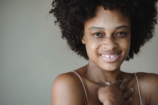 Close-up portrait of a smiling woman with natural afro hair and freckles, embracing natural beauty.