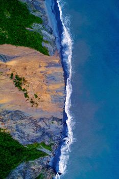 Dramatic aerial view of Taiwan's rugged coast with waves crashing against the cliffs.