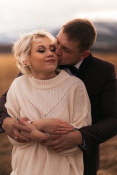 A loving couple shares an intimate embrace in an outdoor autumn setting, expressing romance and warmth.