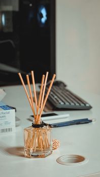 Stylish office desk with a reed diffuser, computer monitor, stationery, and subtle lighting, capturing an elegant worksp