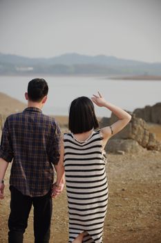 A couple hand-in-hand near a mountain lake, capturing natural beauty and companionship.