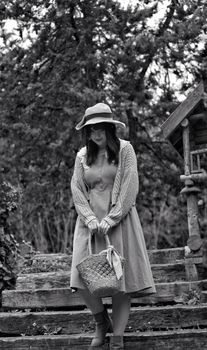 Charming black and white image of a woman in vintage attire in a garden setting.