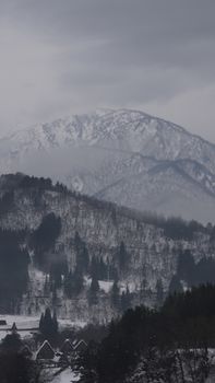 Snow-covered Shirakawa village with mountainous backdrop in winter, creating a serene landscape.