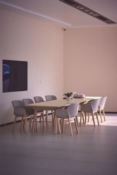 A bright, spacious dining area featuring minimalist decor, a table, chairs, and a wall-mounted TV, perfect for contempor
