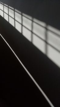 Sunlight casting geometric shadows on a minimalist interior wall.