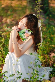 Captivating image of a woman in a white dress holding flowers, basking in nature's embrace.