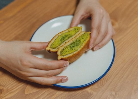 A close-up of matcha-filled dorayaki on a plate being held by hands, offering a traditional Japanese dessert experience.