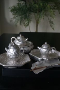 Capture of a sophisticated silver teapot and plate set with Asian artistic influences, perfect for elegant dining.