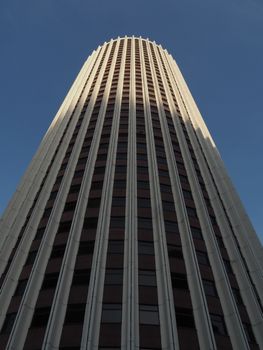 A striking view of a tall skyscraper in Hong Kong, showcasing modern architecture against a clear blue sky.