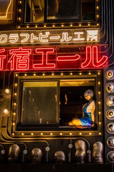 Vibrant night scene from Shinjuku, Tokyo featuring neon lights and a person in a window.