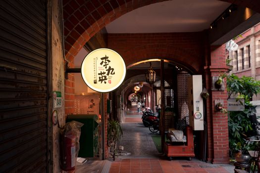 Explore a charming alleyway in Taipei with vintage signage and red brick arches.
