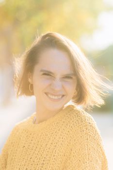 Bright and cheerful portrait of a woman in a yellow sweater, enjoying a sunny day.
