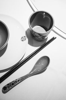 Elegant dining setup featuring chopsticks and a ceramic cup in black and white.