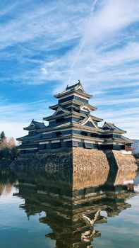 Scenic view of Matsumoto Castle, Japan with perfect reflection on a sunny day.