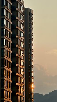High-rise residential buildings reflecting sunset light in Chongqing, China, with mountains in the background.